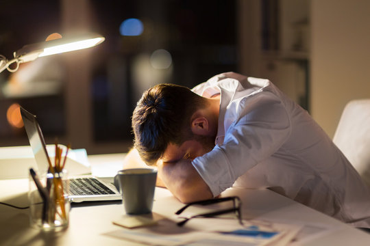 tired businessman lying on table at night office