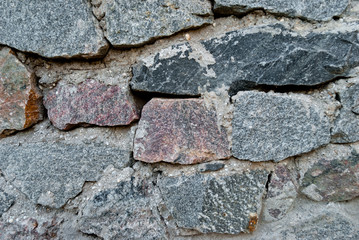 large wall of natural granite stones of different size and color, gray texture on a summer day, multi-colored granite natural stone, pieces of stone, splinters, texture pattern, stone wall, masonry