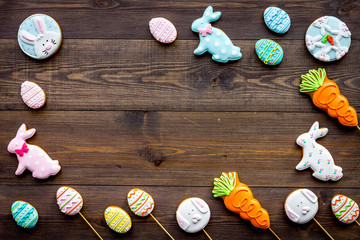 Obraz na płótnie Canvas Easter background. Cookies in shape of easter bunny and easter eggs. Dark wooden background top view copy space