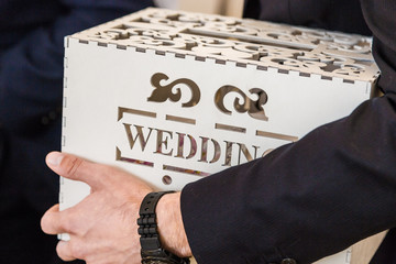 Man holds in his hand a wedding box with a wedding inscription for wedding greetings and gifts.