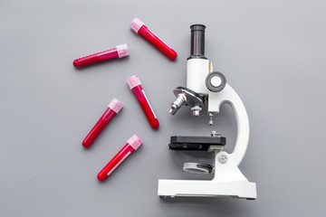 Do blood test in laboratory. Analysis. Blood samples in test tubes near microscope on grey background top view copy space