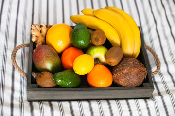 Fresh delicious fruits in a wooden box on the bed. Summer healthy raw vegan clean eating breakfast concept. Close up, copy space.