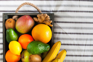 Fresh delicious fruits in a wooden box on the bed. Summer healthy raw vegan clean eating breakfast concept. Close up, copy space.