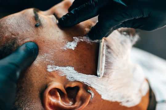Barber shaving beard of customer
