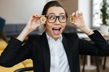 Young excited business woman showing her golden bitcoins