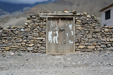 Old wooden gate in a stone wall in the Himalayan mountains. Old Kagbeni. Upper Mustang. Nepal.