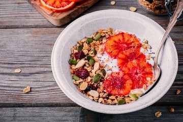 healthy breakfast bowl of homemade granola with fresh yogurt and blood slices oranges