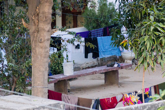 Clothes drying in the middle of a huge courtyard with a bench and trees all around. Shows the huge living spaces that are available in smaller towns