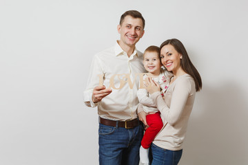 Joyful smiling young man, woman holding, hugging little cute child boy with wooden word Love isolated on white background. Father, mother, little kid son. Parenthood, family, parents, children concept