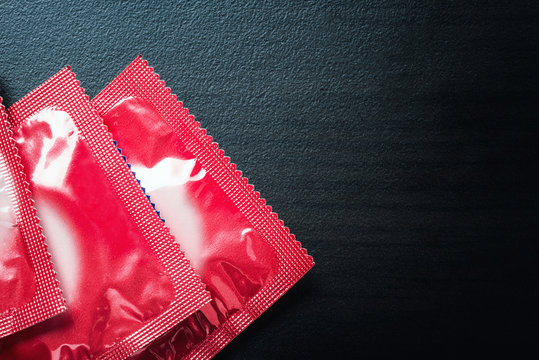 Red Condoms on Black Wooden Table - Safe Sex Concept