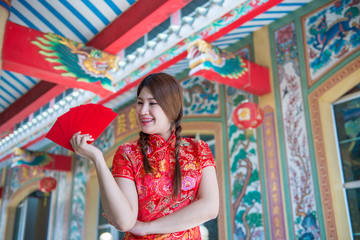 Portrait of beautiful asian woman in Cheongsam dress with Red envelope in hand,Thailand people,Happy Chinese new year concept