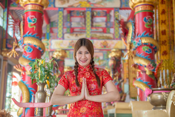Portrait of beautiful asian woman in Cheongsam dress ,Thailand people,Happy Chinese new year concept,Make hand sawasdee
