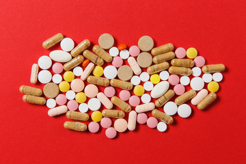 Medication white colorful round tablets arranged abstract on red color background. Aspirin, capsule pills for design. Health, treatment, choice healthy lifestyle concept. Copy space for advertisement.