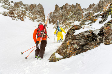 Extreme skiers climb to the top along the couloir between the rocks before the descent of the...