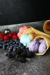 Set of ice cream scoops of different colors and flavours with blueberries, raspberries and blackberries.