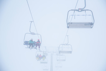 Ski lift in ski resort. Silhouette of skiers, white background