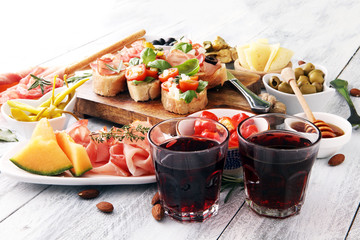 Italian antipasti wine snacks set. Cheese variety, Mediterranean olives, pickles, Prosciutto di Parma, tomatoes, artichokes and wine in glasses