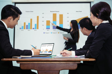 A girl present to her team in meeting by using graph on whiteboard