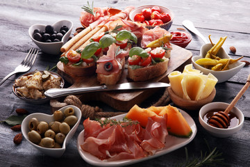 Italian antipasti wine snacks set. Cheese variety, Mediterranean olives, pickles, Prosciutto di Parma, tomatoes, artichokes and wine in glasses