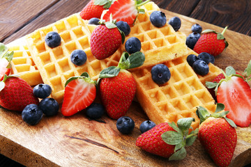 Board of belgian waffles with fresh berries on wooden background
