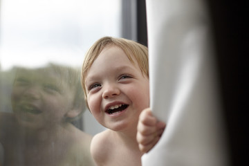 Portrait of smiling toddler boy by window