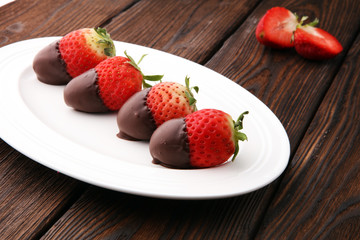 Chocolate dipped strawberries at dessert bar on white plate.
