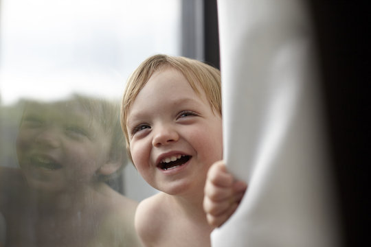 Portrait of smiling toddler boy by window