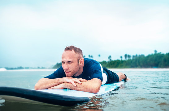 Man surfer rests lying on surfboard