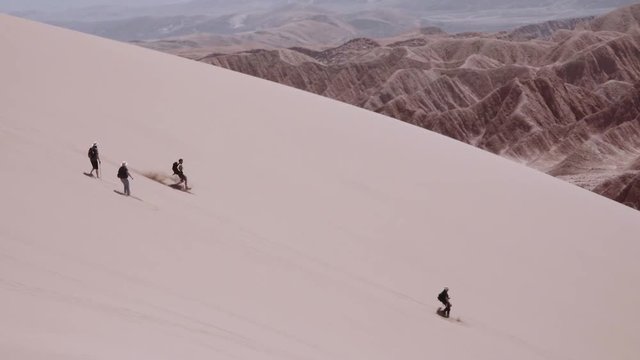 SAN PEDRO DE ATACAMA, CHILE - CIRCA DECEMBER 2017: People runs down over the sand dunes of the dead valley, Atacama desert, Chile. Slow motion