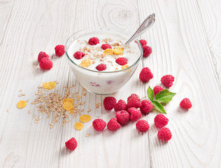 Bowl of homemade yogurt with muesli and fresh raspberry on wooden table. Fresh yogurt. Healthy food concept. High resolution product.