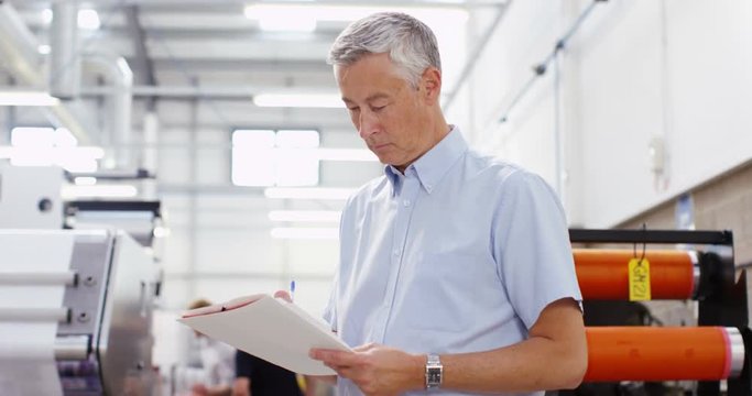 4K Serious business manager in printing factory looking down at paperwork