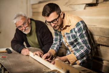 Father and son working with a piece of wood