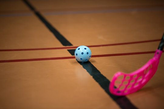 Close up of floorball stick and blue ball in the gym