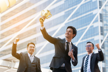 Success business man holding golden trophy cup with right hand, Business executives rejoice in...