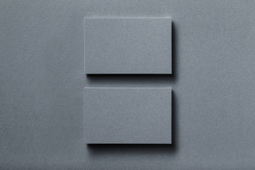 Mockup of two horizontal silver metallic business card stacks at textured designer paper background.