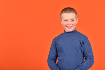 Cheerful cheerful boy. Good mood. Boy on an orange background.