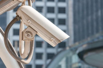 Modern cream CCTV video recorder hanging on roof with blur building background.  Security camera evidence in central city.