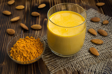 Almond milk with turmeric on the rustic  wooden background