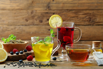 te' infuso tisana di erbe e frutta tre bicchieri su sfondo tavolo rustico di legno