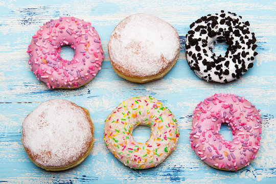 Traditional donuts on wooden background.  Tasty doughnuts with icing and powdered sugar, copy space