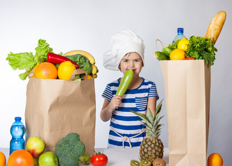 Little happy girl in chef hat with big bags of fruits and vegetables Positive human emotion, facial...