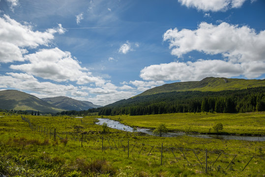 Mountain landscape in the Glencoe area in Scotland, Springtime view mountains with grassland and countryside road in the valley of the Scottish highland near Glencoe