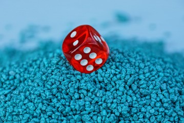 один красный игровой кубик в куче мелких синих камней - obrazy, fototapety, plakaty