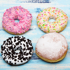 Traditional donuts on wooden background.  Tasty doughnuts with icing and powdered sugar, copy space