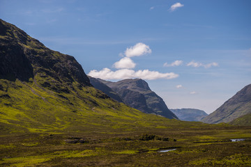 Naklejka premium Mountain landscape in the Glencoe area in Scotland, Springtime view mountains with grassland and countryside road in the valley of the Scottish highland near Glencoe