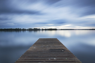 Fototapeta premium The jetty at the Valkenburg lake on a cloudy evening.