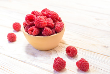Fototapeta na wymiar Raspberries bowl on rustic wood background, top view with copy space. Organic berries on wooden table