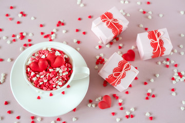 Festive background.  Coffee cup, full of multicolor sweet sprinkles sugar candy hearts and packing Valentine's  Day gifts.  Love and Valentine's day concept.