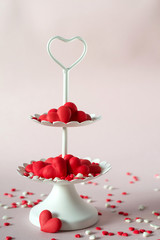 White two tier serving tray full of multicolor sweet sprinkles sugar candy hearts.  Love and Valentine's day concept.