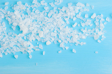 large crystals of rock salt on a blue wooden background